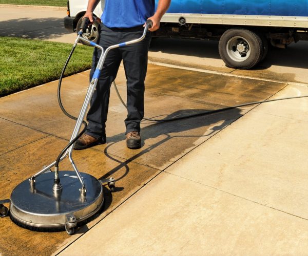 man pressure washes driveway with pressure washer surface cleane